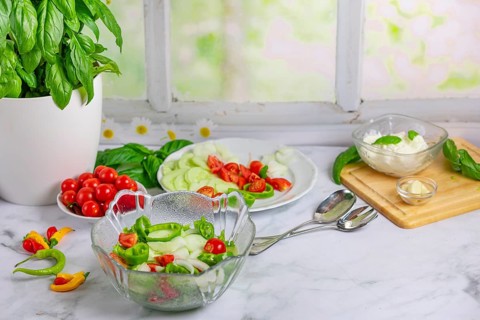 Fresh vegetables on board and plate, salad ingredients, cucumber, tomatoes, basil, pepperoni,