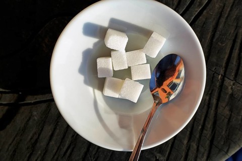 A pile of sugar pieces, sugar cubes and a coffee spoon on a saucer in a café, symbolic image