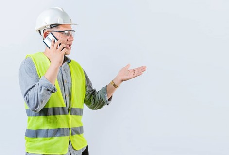 Young engineer calling on cell phone isolated. Civil engineer talking on phone isolated on white