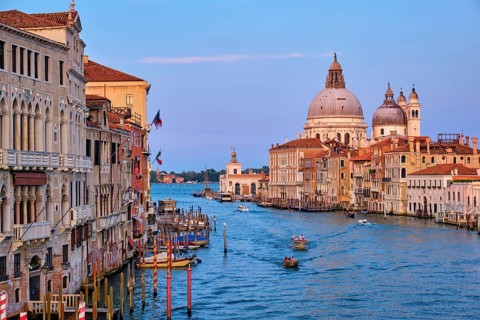 Panorama of Venice Grand Canal with boats and Santa Maria della Salute church on sunset from Ponte