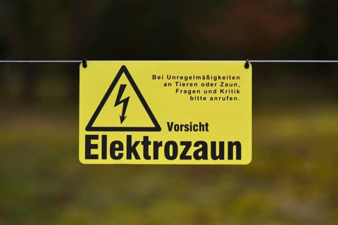 Leimen, Germany, April 2020: Yellow electric fence warning sign with German text saying 'Attention,