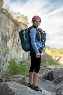 Portrait of female climber looking at camera at foot of rocky mountain. Extreme outdoor sport