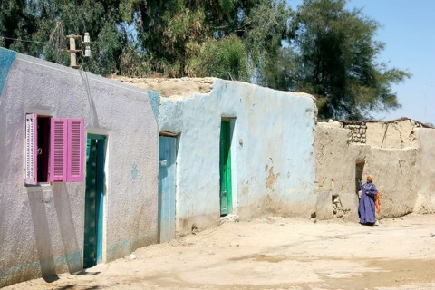 Bedouin woman in street with traditional houses in the Farafra Oasis in the Western Desert, Egypt,