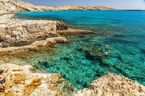 Tourists bathing in the crystal-clear turquoise waters of the Cape Greco peninsula, Agia Napa,