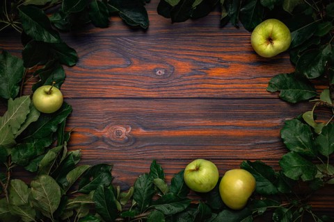 Frame of apple tree leaves and apples on wood, copying room
