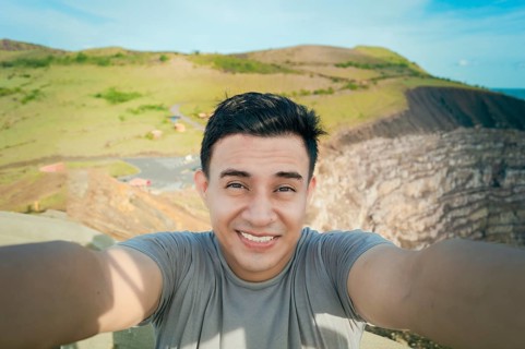 Adventurous man taking a selfie at a viewpoint. Close up of person taking an adventure selfie,
