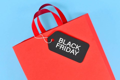 Black Friday sale label on red paper shopping bag on blue background