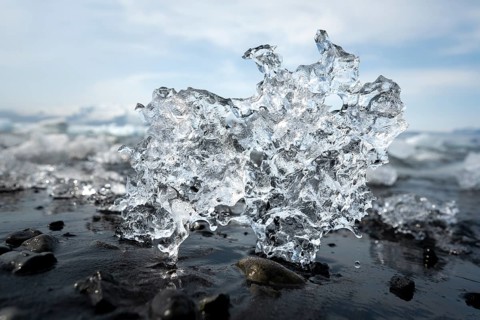 Ice, piece of ice on black pebble beach, Jökulsárlón glacier lagoon, glacial lake, southern edge of