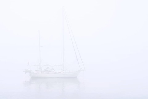 Sailboat, sailing boat, yacht with lowered sails anchored at sea during bad visibility due to thick