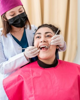 Dentist checking patient with excavator and dental mirror, Front view of dentist checking patient