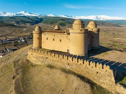 The Renaissance castle of La Calahorra against the snow-capped Sierra Nevada mountain range, aerial