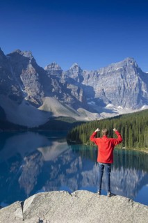Tourist with open arms on look-out point looking over Moraine Lake in the Valley of the Ten Peaks,