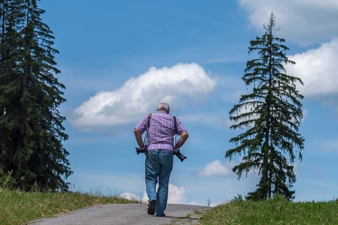 Photographer with equipment looking for motifs in the mountains, Eisenberg (Ostallgäu), Bavaria,