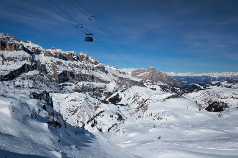 View of a ski resort piste with people skiing in Dolomites in Italy with cable car ski lift. Ski