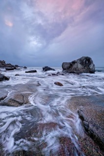 Rocks on beach of fjord of Norwegian sea in winter on sunset. Utakliev beach, Lofoten islands,