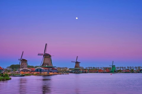 Windmills at famous tourist site Zaanse Schans in Holland in twilight on sunset with moon. Zaandam,