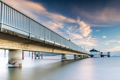 A long jetty over a calm lake with a slightly cloudy sky and daylight, harbour, Immenstaad, Lake