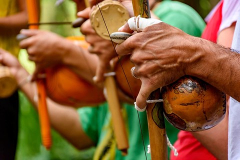 Hands of a musician playing an Afro Brazilian percussion musical instrument called a berimbau