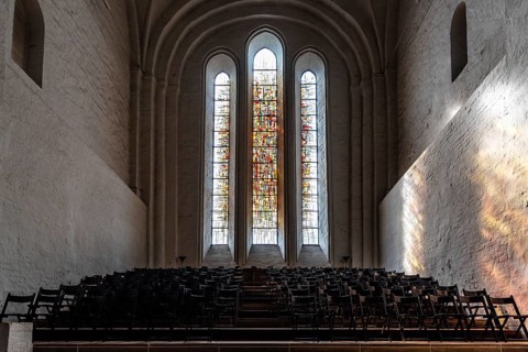 Lubeck, Germany, August 3, 2019: Stained glass window and chairs in the interior of the Cathedral,