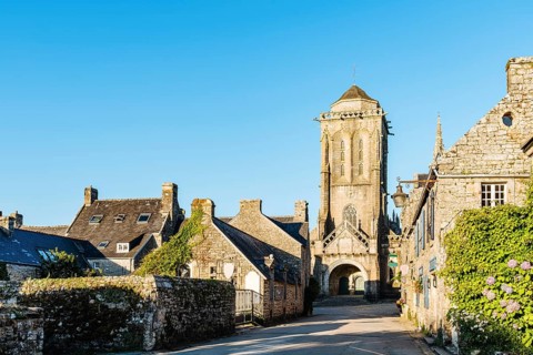 View of the main street of the medieval village of Locronan with the church on background a sunny