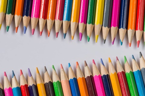 Abstract composition of a set wooden colour pencils against a white background