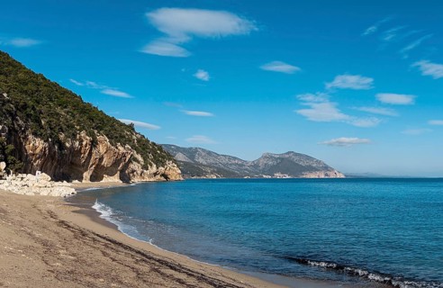 The overhanging cliffs and sandy beach at Cala Luna on the east coast of Sardinia