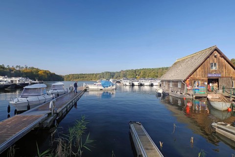 Spacious harbour with boats and jetty, wooden hut on the shore, blue water, fish shop, Eldenburg,