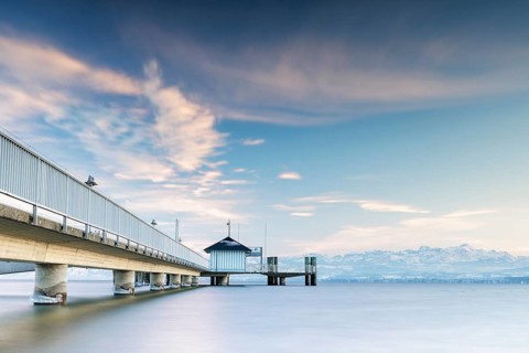 A jetty over a lake with a view of mountains and a cloudy sky in a quiet atmosphere, harbour,