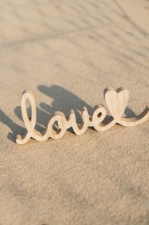 Wooden word love on sandy beach background. Concept of romantic holiday anniversary, proposal,