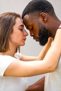 Close-up of multiracial lovers face to face with eyes closed embraced tenderly