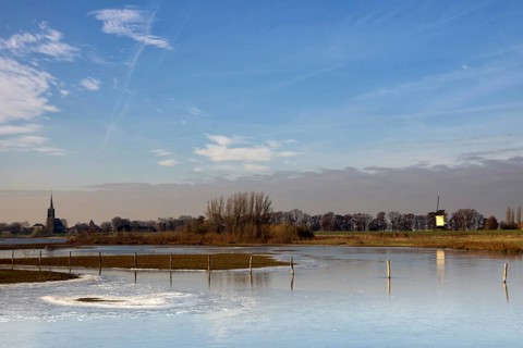 Frozen river foreland from the river Maas near the Dutch village Batenburg with the church tower