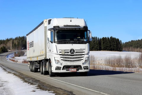 White Mercedes-Benz Actros 2653 truck pulls DB Schenker semi trailer along highway on a sunny day