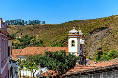 Tower of historic baroque church among the houses, roofs and hill in the city of Ouro Preto in