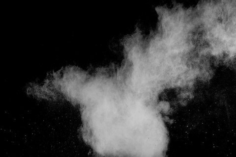 Freeze motion of white dust particles on black background. White powder explosion