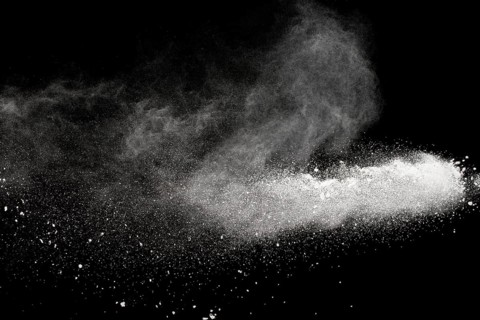 Bizarre forms of white powder explosion cloud against black background.White dust particles splash