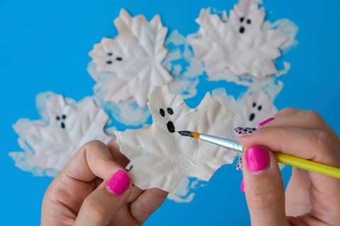 Maple leaf with painted face as decoration for autumn Halloween holiday celebration. Halloween