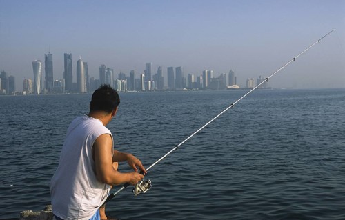 13.09.2010, Doha, Qatar Qatar, A man fishing on the promenade along Al Corniche Street with a view