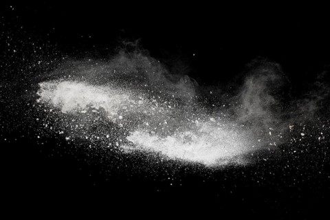 Bizarre forms of white powder explosion cloud against black background.White dust particles splash