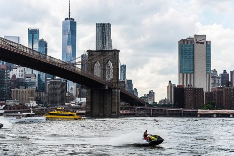 New York City, USA, June 24, 2018: Cityscape of Downtown of Manhattan and Brooklyn Bridge with jet