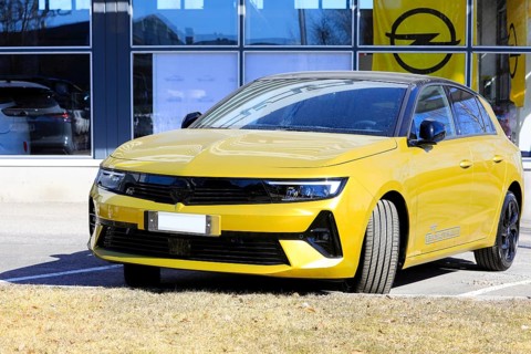 New, yellow Opel Astra parked outside a dealership. The new 6th generation of Astra is available