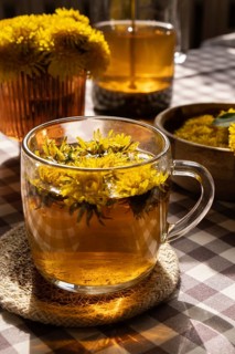 Dandelion flower healthy tea in glass teapot and glass cup on table. Delicious herbal tea from