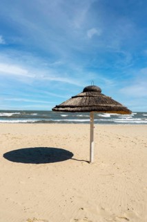 Straw beach rattan parasol at the empty beach with blue sky backgrounds sea ocean coast. Relaxing