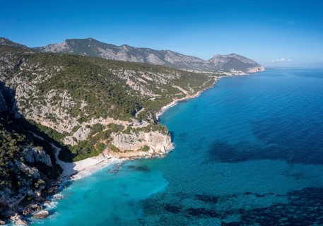 Aerial view of the rugged mountainous coast near Cala Gonone with turqouise water and small white