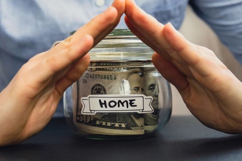Unrecognizable woman holding Saving Money In Glass Jar filled with Dollars banknotes. HOME