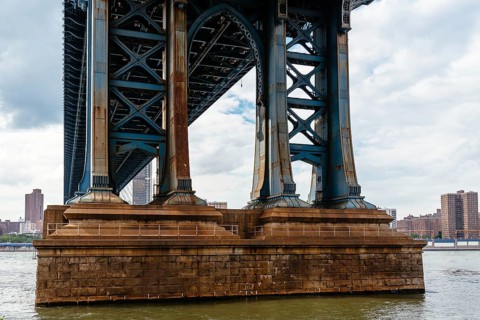 Detail of Pillar of Manhattan Bridge against cityscape of New York City. Steel Abutment With Bolt