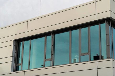 Modern office building with large windows that reflect the blue sky and emphasise the modern