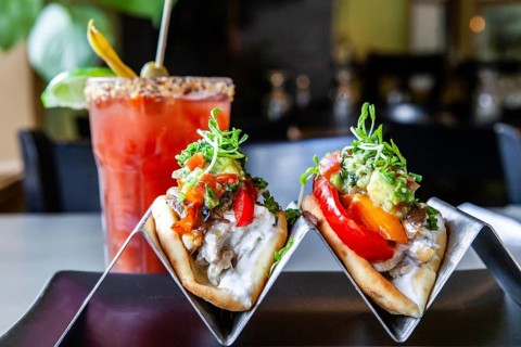 A closeup and front view of two healthy tacos filled with fresh vegetables, served with a