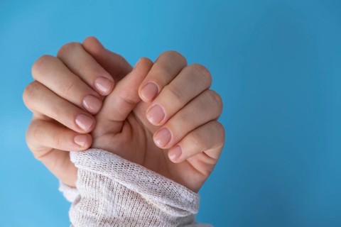 Pastel softness manicured nails on blue background. Woman showing her new manicure in colors of