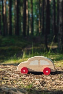 Wooden toy car on greenery forest background. Eco-car concept World car free day electric vehicle