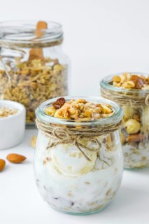 Healthy breakfast. Oatmeal Granola with greek yogurt and nuts banana muesli in jars on light